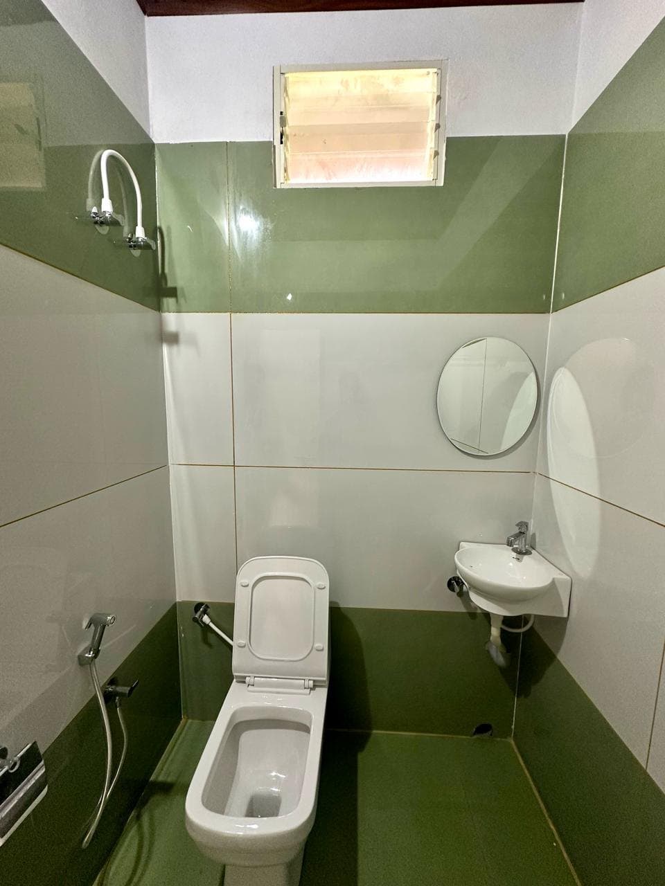 Second bathroom with green and white tiles and a wall-mounted basin