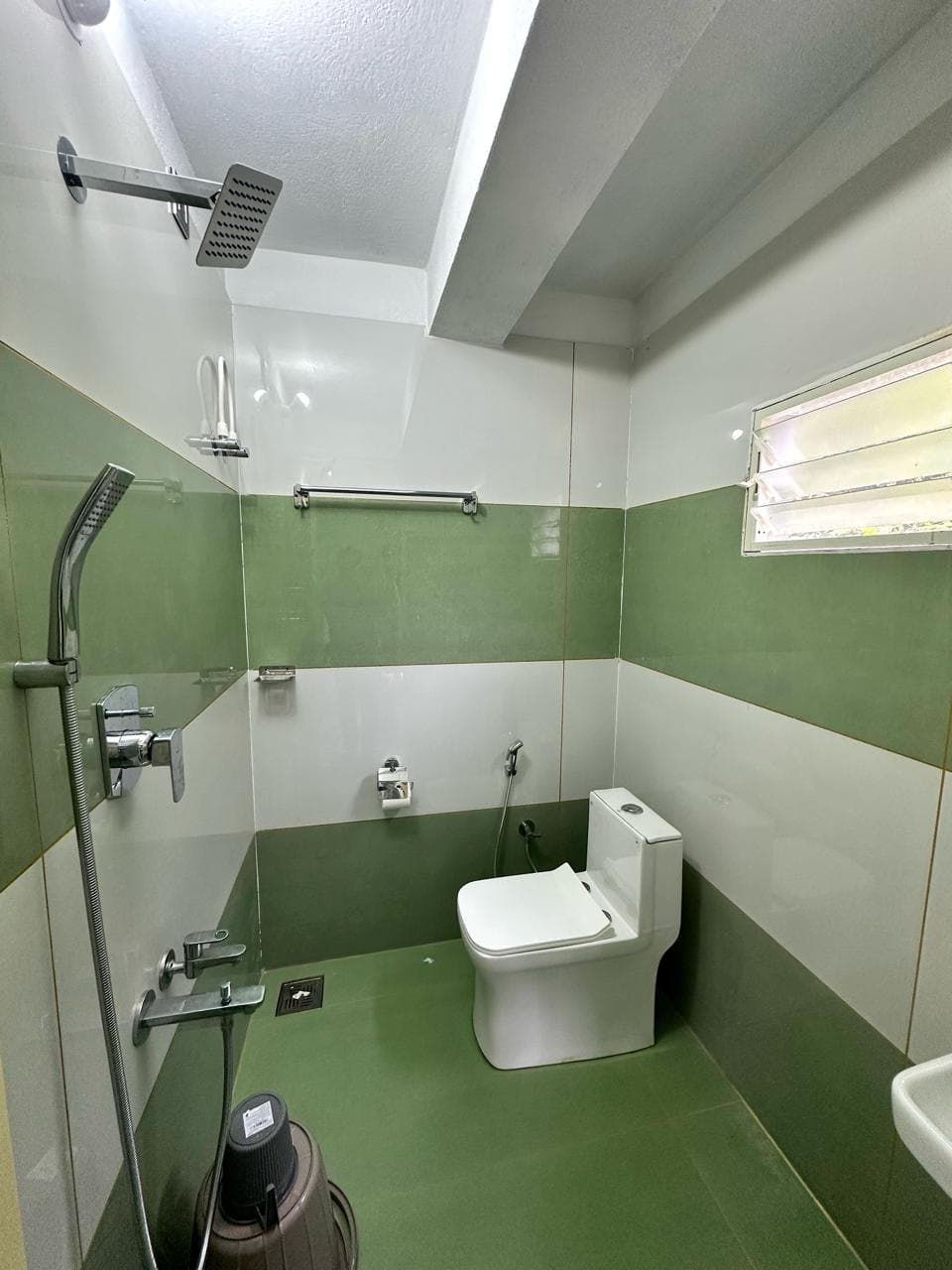 Bathroom with green and white tiles and a rain shower