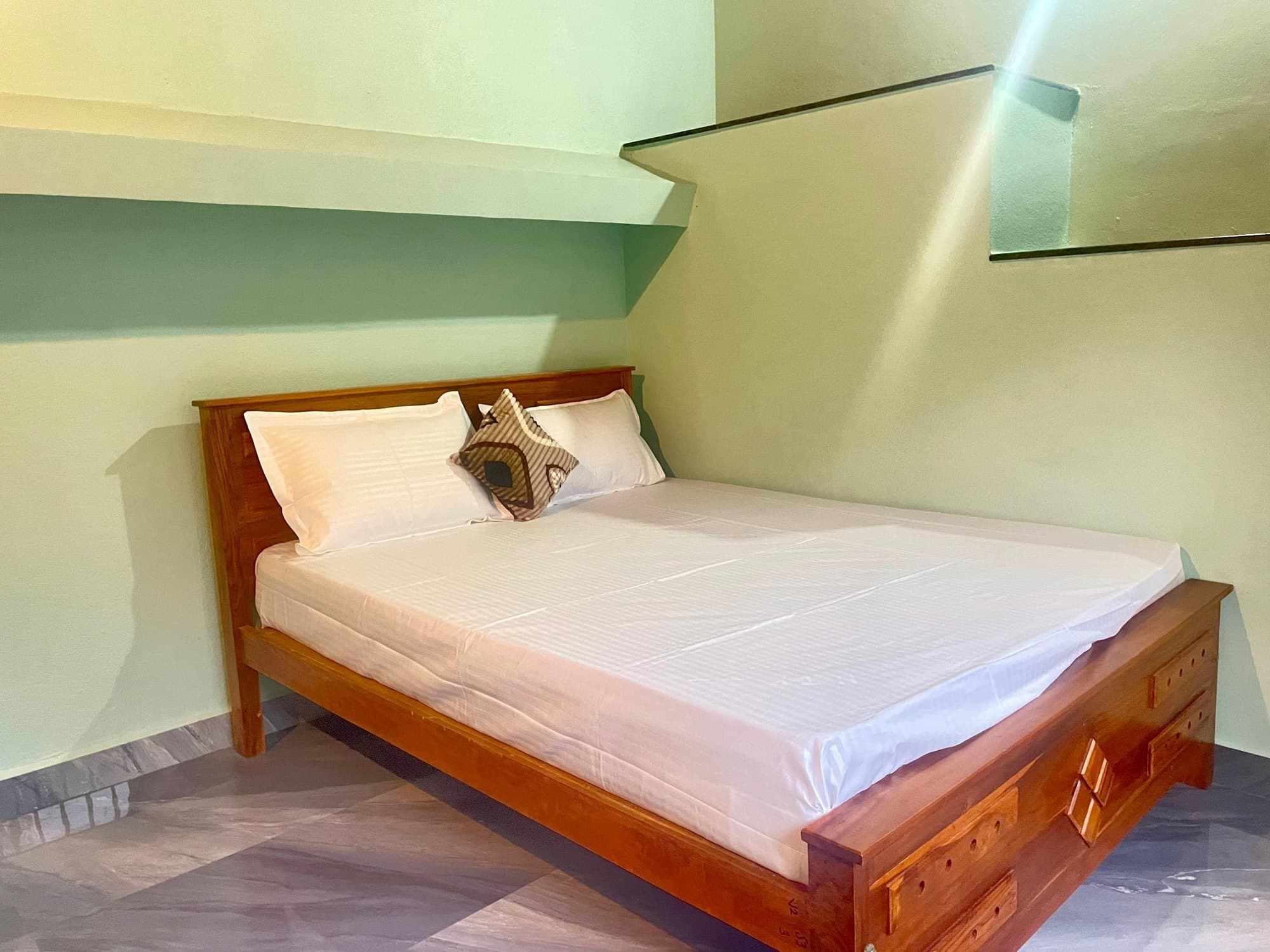 Teak double bed with white linen and cushions
