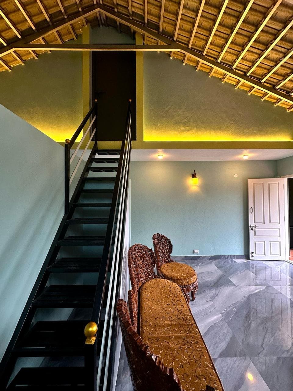 Upper-level living area at Leaflink with a staircase, carved wooden seating and a wood-beamed ceiling